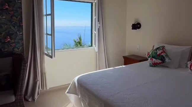 Double bed beside an open window with the sea beyond