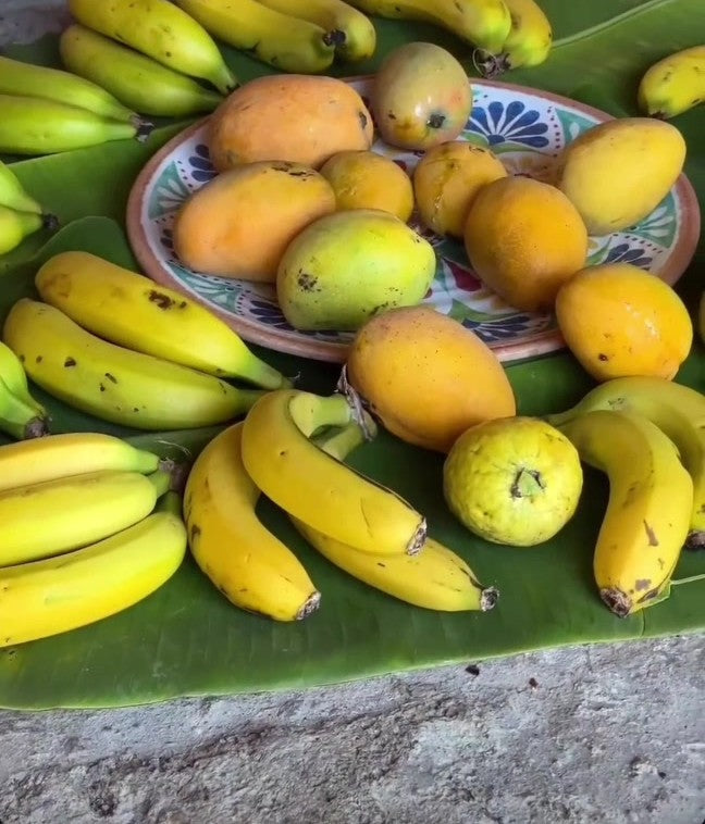 Mangoes, bananas and guavas from the garden on a banana leaf