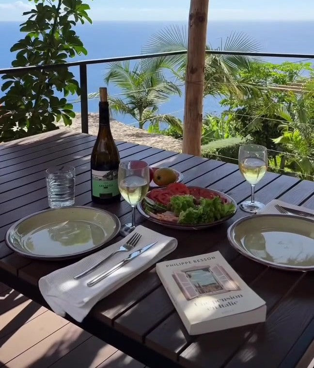 Table set for two with wine and salad, looking out to the sea