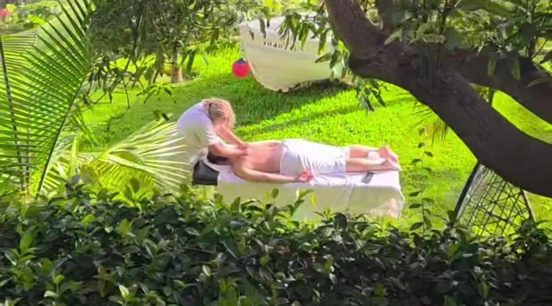 A guest receiving a massage on the lawn among the trees